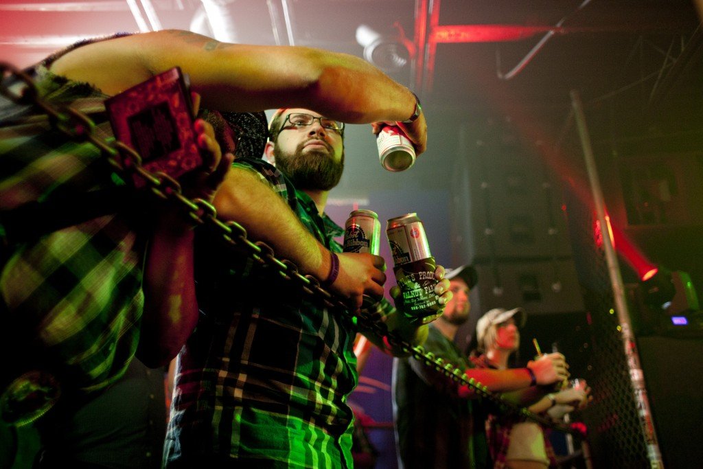 Fans hold beers and lean over a chain barrier while watching the Whitey Morgan and the 78's show at The Machine Shop in Flint, MI on May 1, 2015.